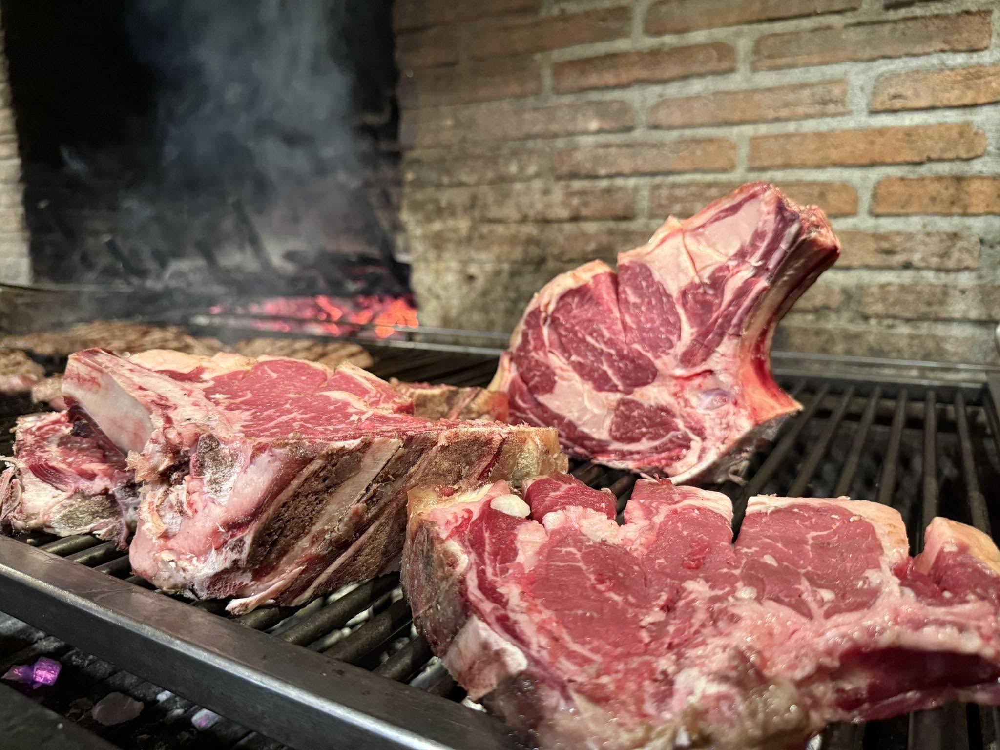 Costate e tagli di carne sulla griglia del camino a legna