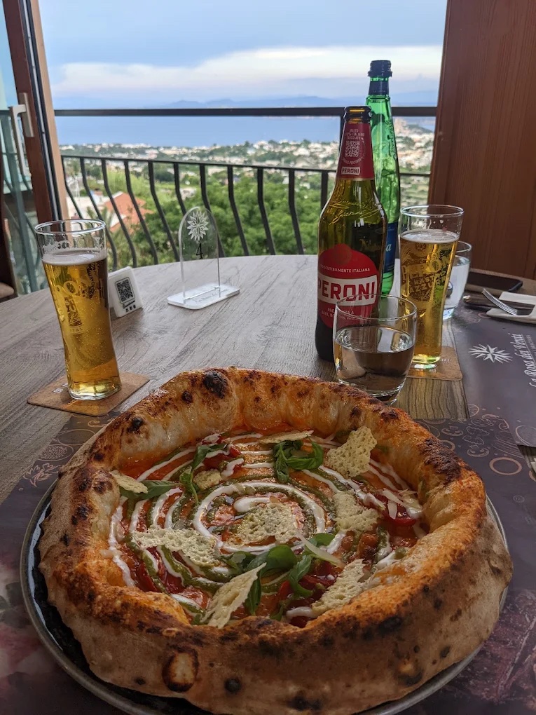 Pizza e birra su un tavolo della terrazza panoramica, con vista sul golfo